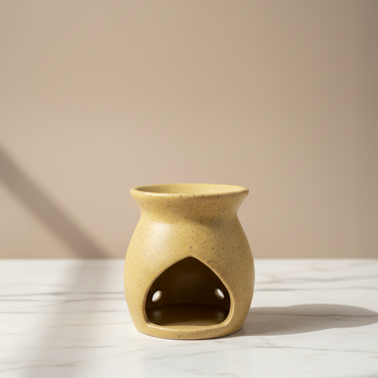 Beige ceramic oil burner on a white surface with a beige background