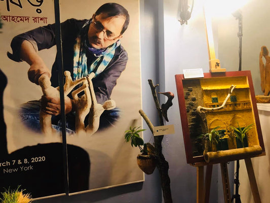 Gallery display with poster of artist Akhtar Ahmed Rasha wooden sculptures and carved wooden artwork on easel