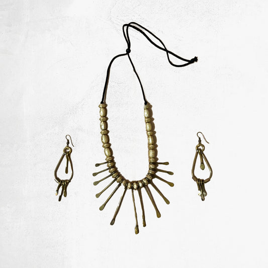 A tribal jewellery set featuring a brass sunburst necklace with pointed rays and matching elongated drop earrings with textured details.