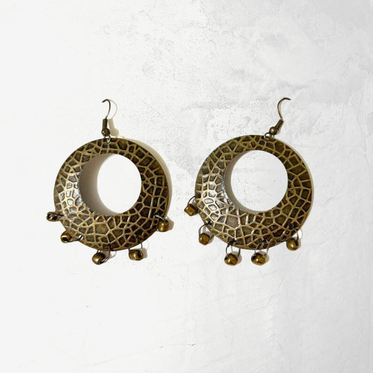 A pair of rustic textured metal hoop earrings with a dappled finish and dangling bronze-toned beads on a white background.